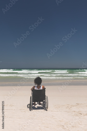 Young woman disable sitting on wheelchair at beach 