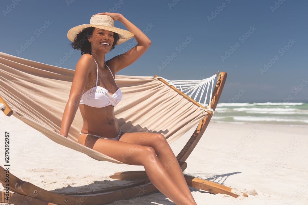 Woman sitting on hammock at beach on a sunny day