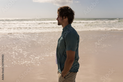 Young man with hand in pocket standing on beach