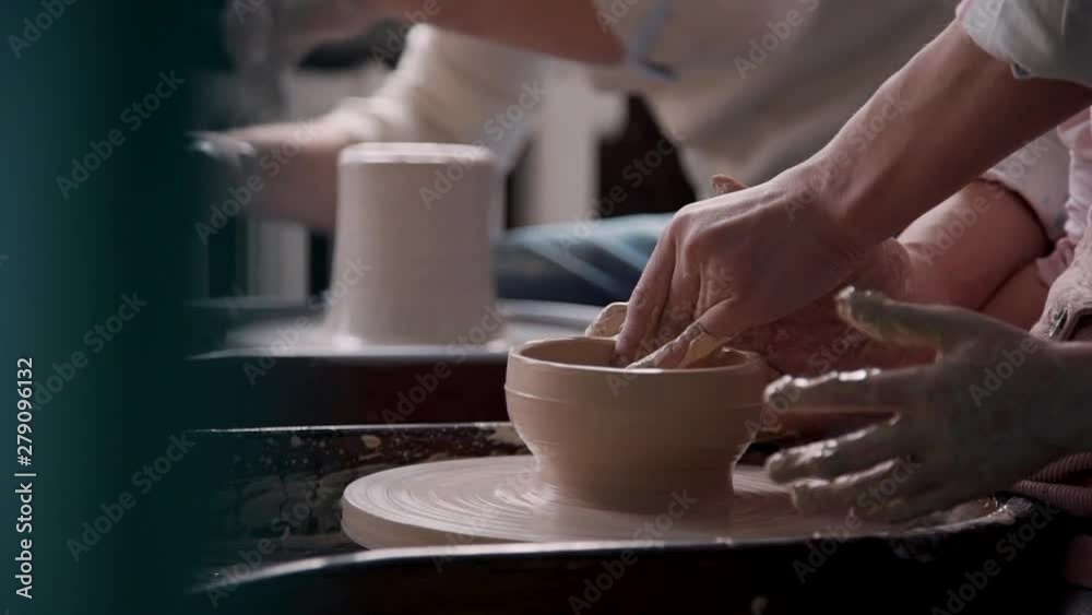 Adult sculptor working with raw clay in cozy class room or work place studio with soft daylight inside. Happy family spending free weekend time together and making craft objects for fun Adult sculptor working with raw clay in cozy class room or work place studio with soft daylight inside. Happy family spending free weekend time together and making craft objects for fun