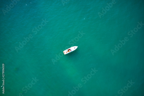 Yacht white blue awning on turquoise water, top view. Aerial photography with drone. 