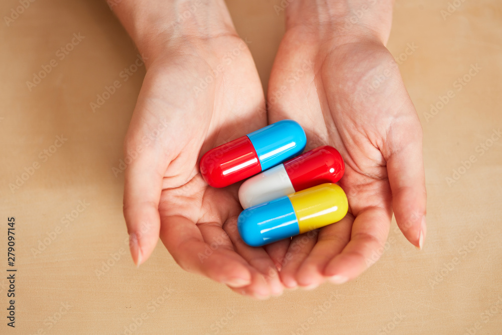 Hands hold three big pills or medicines