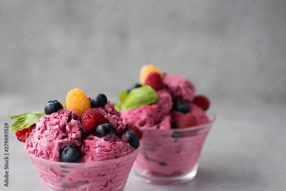 Homemade ice cream made from fresh berries with basil in glass bowl on a gray background. Homemade ice cream made from fresh berries with basil in glass bowl on a gray background.