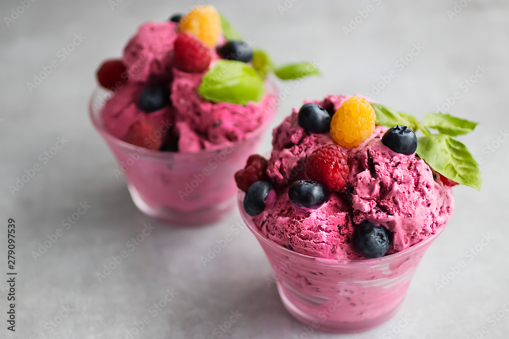 Homemade ice cream made from fresh berries with basil in glass bowl on a gray background. Homemade ice cream made from fresh berries with basil in glass bowl on a gray background.