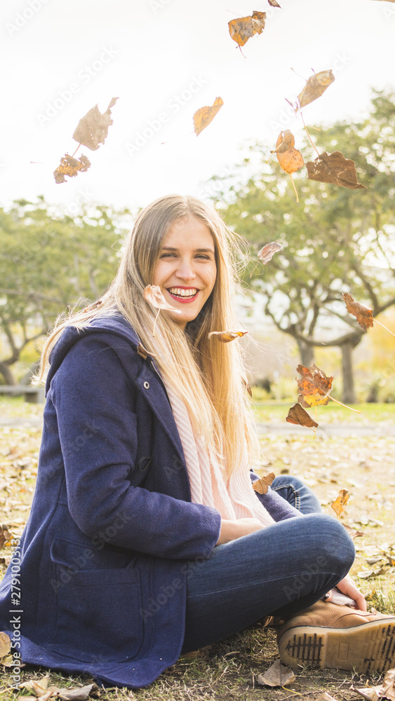 Attractive model sitting on autumn ground and smiling at camera Attractive model sitting on autumn ground and smiling at camera