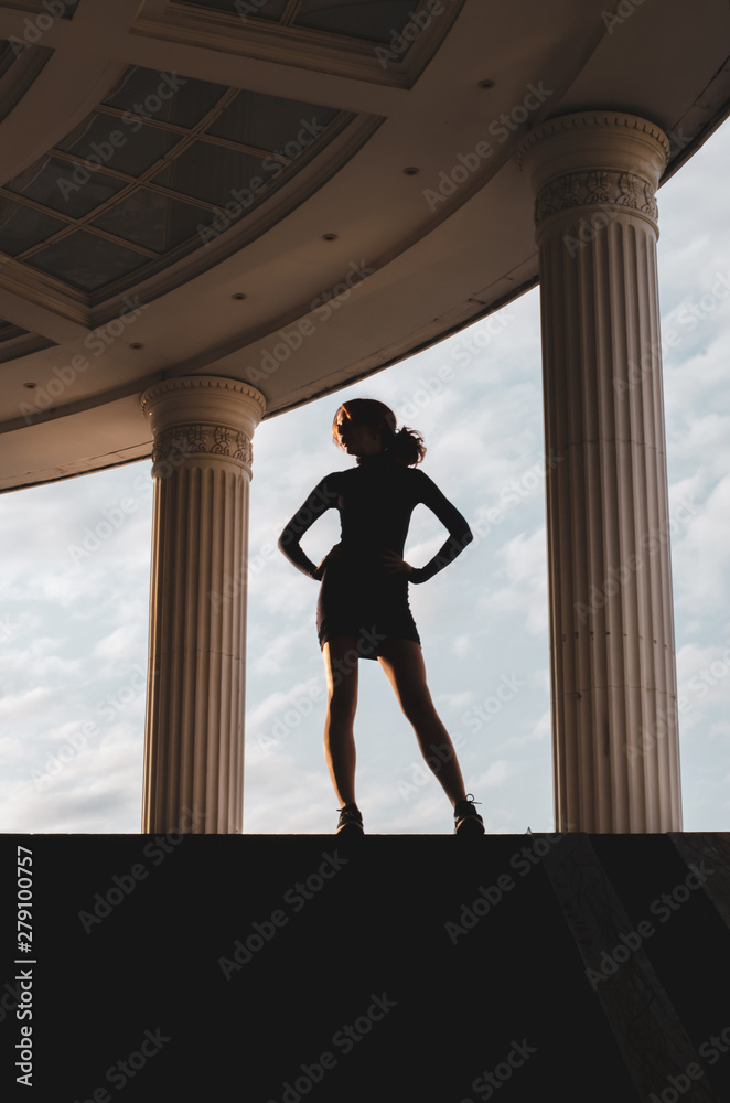 Silhouette of a slender girl on the street. Beautiful curly girl in summer. Silhouette of a slender girl on the street. Beautiful curly girl in summer.