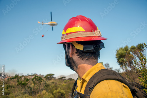 Wildland firefighter watching turning helicopter at wildfire