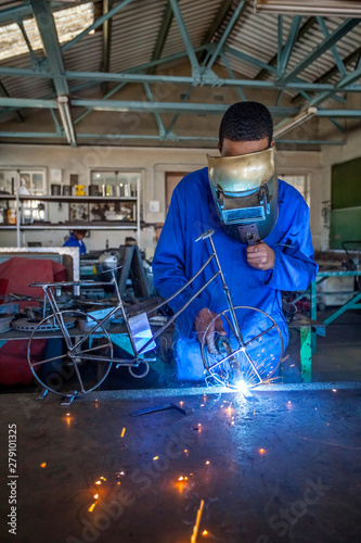 Students welding in a workshop. Boy welding a bike out of metal wire.