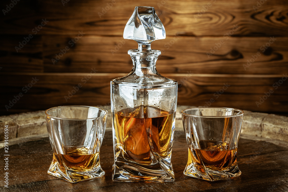 Two glasses of brandy or cognac and bottle on the wooden table Two glasses of brandy or cognac and bottle on the wooden table