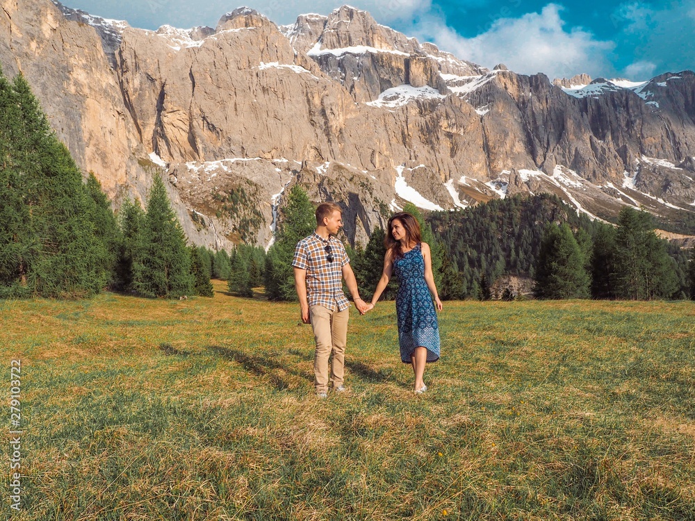 Naklejka premium Brunette girl hugging a boy, walking on the lawns in the mountains.