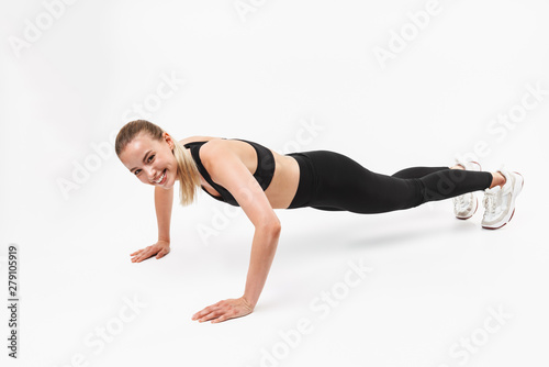 Optimistic young sports fitness woman posing isolated over white wall background make push-ups exercises.