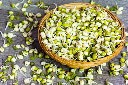 Top view of green fresh mungo sprouts in a wicker bowl on a jute background. Food photography. Minimalist photography.