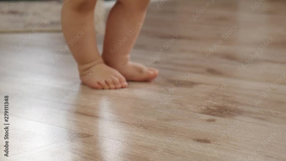 Close up view of babies feet during making her first steps slow motion Close up view of babies feet during making her first steps slow motion