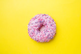 Pink doughnut on a yellow background. Top view Flat lay.