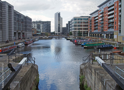 a view of clarence dock in leeds with moored barges and people walking around the surrounding buildings photo