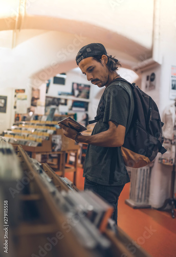 Young male in a music store grabs a disc with his hand