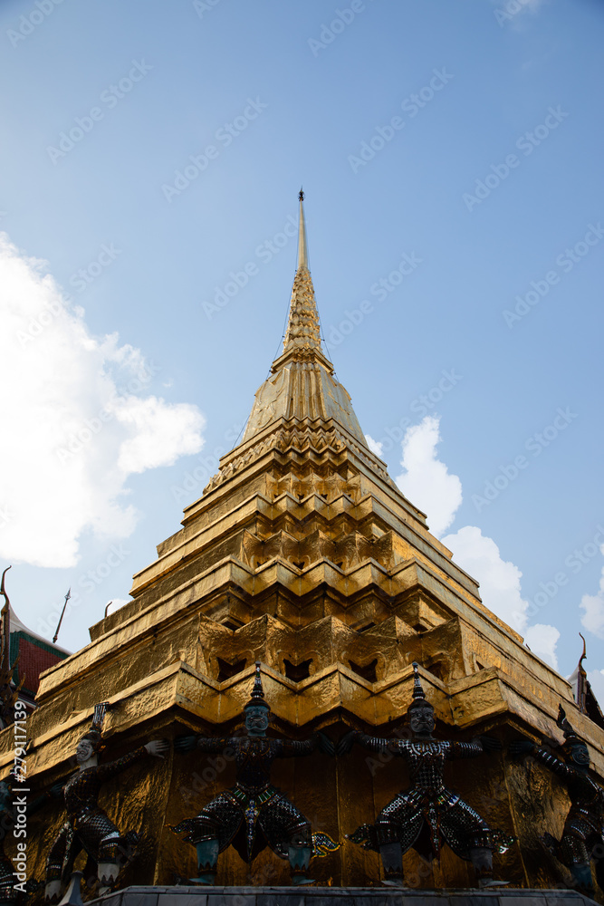 Low angle view of a golden pagoda from the Emerald Buddha Temple with white and clouds in the background Low angle view of a golden pagoda from the Emerald Buddha Temple with white and clouds in the background