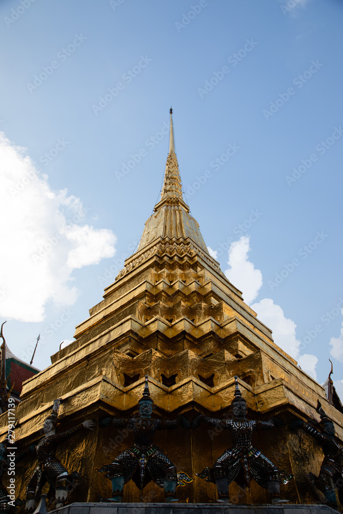 Low angle view of a golden pagoda from the Emerald Buddha Temple with white and clouds in the background