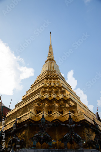 Low angle view of a golden pagoda from the Emerald Buddha Temple with white and clouds in the background