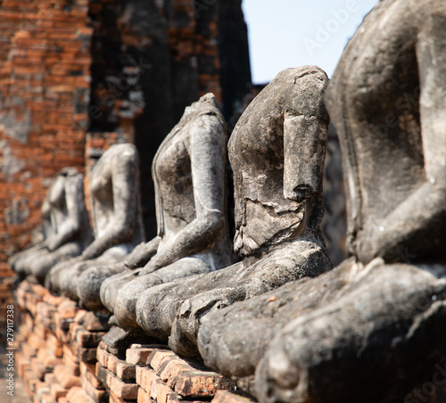 Close up of ancient stone buddha statues placed in line in the ruined temple at Ayutthaya