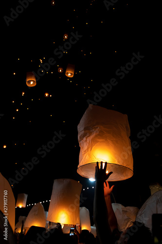Unrecognizable man releasing paper lantern during Loi Krathong and Yi Peng festival in Chian Mai