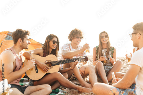 Group of cheerful happy friends camping at the beach