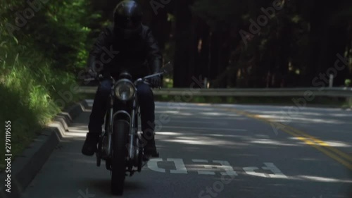 Motorcyclist With Leather Jacket Riding on a Wooded Road photo