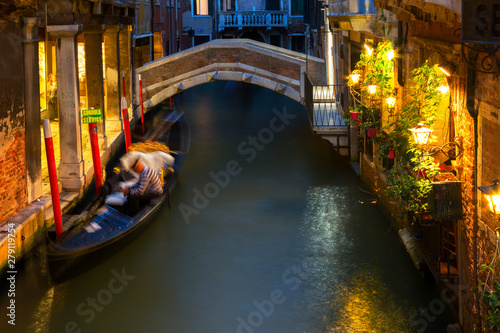 Gondolier is resting waiting for tourists, Venetian canals at night.