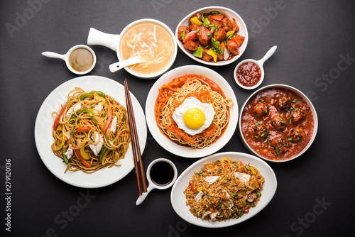 Assorted Indo chinese food in group includes non vegetarian or chicken Schezwan/Szechuan hakka noodles, fried rice, manchurian, egg american chop suey, soup with spoon and chop sticks, selective focus photo