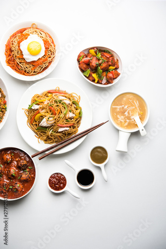 Assorted Indo chinese food in group includes non vegetarian or chicken Schezwan/Szechuan hakka noodles, fried rice, manchurian, egg american chop suey, soup with spoon and chop sticks, selective focus