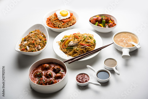 Assorted Indo chinese food in group includes non vegetarian or chicken Schezwan/Szechuan hakka noodles, fried rice, manchurian, egg american chop suey, soup with spoon and chop sticks, selective focus