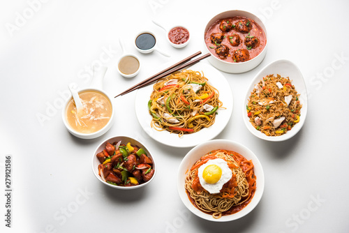 Fototapeta Naklejka Na Ścianę i Meble -  Assorted Indo chinese food in group includes non vegetarian or chicken Schezwan/Szechuan hakka noodles, fried rice, manchurian, egg american chop suey, soup with spoon and chop sticks, selective focus