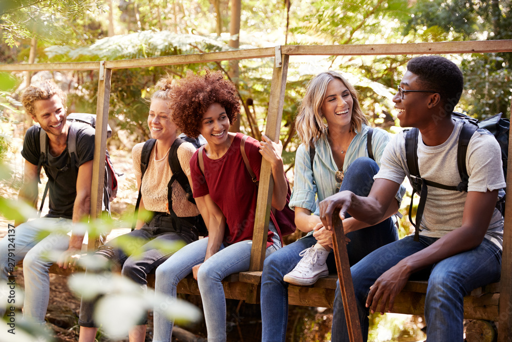 Five young adult friends on a hike sitting together talking during a break, close up