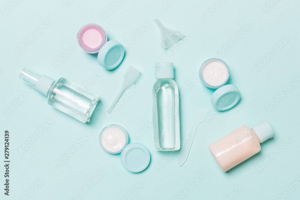 Set of travel size cosmetic bottles on blue background. Flat lay of cream jars. Top view of bodycare style concept Set of travel size cosmetic bottles on blue background. Flat lay of cream jars. Top view of bodycare style concept