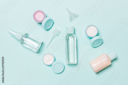 Set of travel size cosmetic bottles on blue background. Flat lay of cream jars. Top view of bodycare style concept