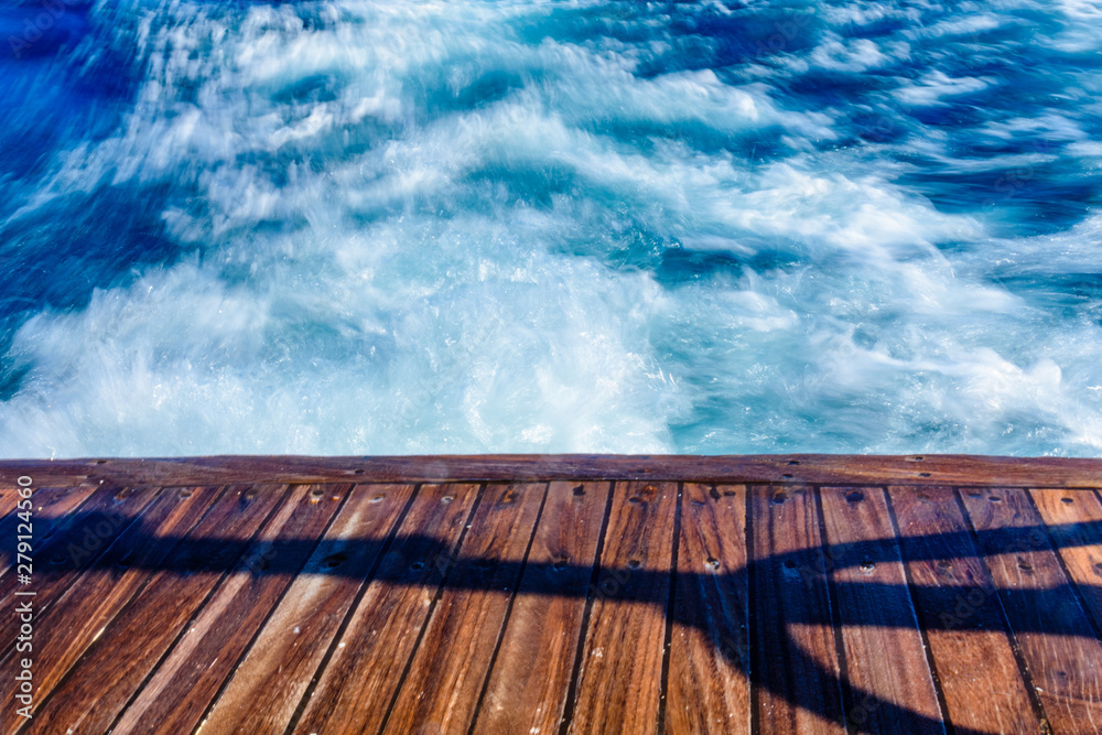 Wave trace with white foam on a water surface behind of fast moving yacht