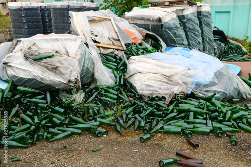 abandoned glass factory. packed bottles in pallets  broken bottles on asphalt  lots of loose bottles and garbage from production. devastation  separation  bankruptcy of  enterprise.