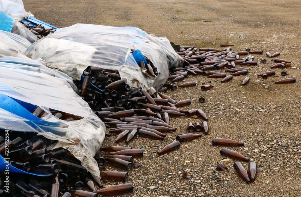 Obraz premium abandoned glass factory. packed bottles in pallets, broken bottles on asphalt, lots of loose bottles and garbage from production. devastation, separation, bankruptcy of enterprise.