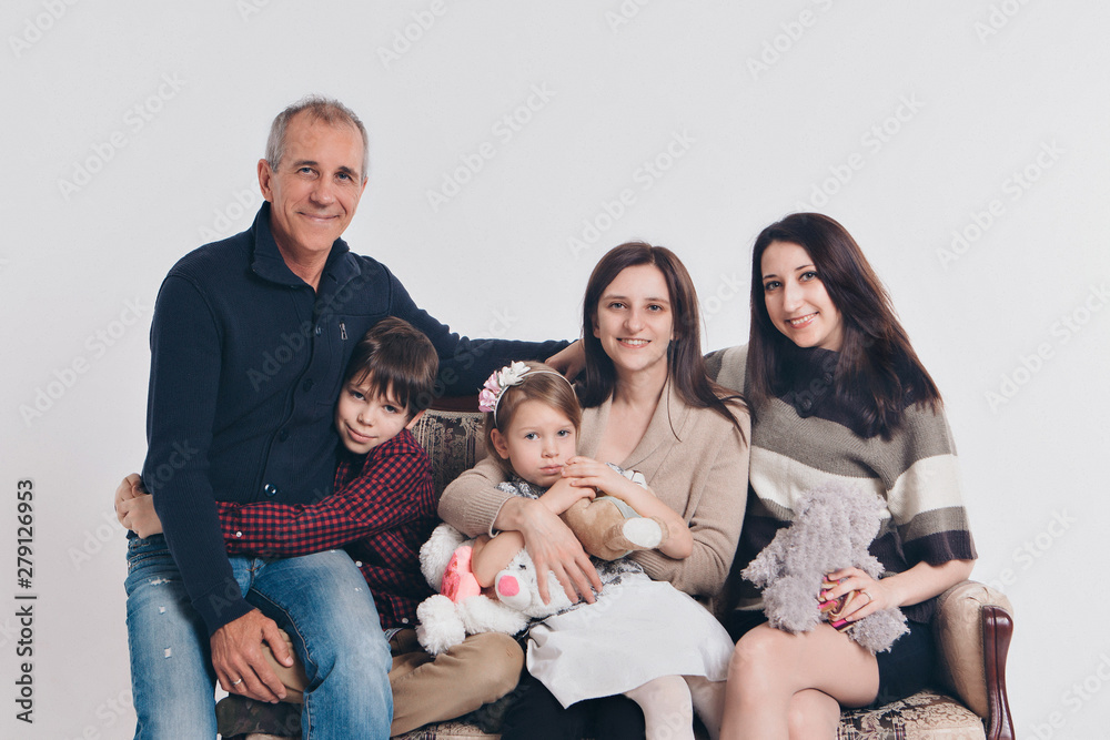 concept of happy childhood, family, love - group of people on a white background: adults and children with toys sitting on the same couch