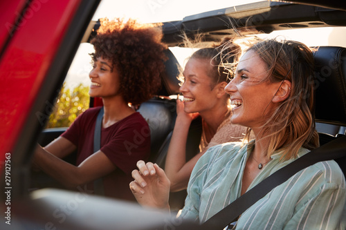 Three millennial female friends on a road trip driving together in an open jeep, close up © Monkey Business
