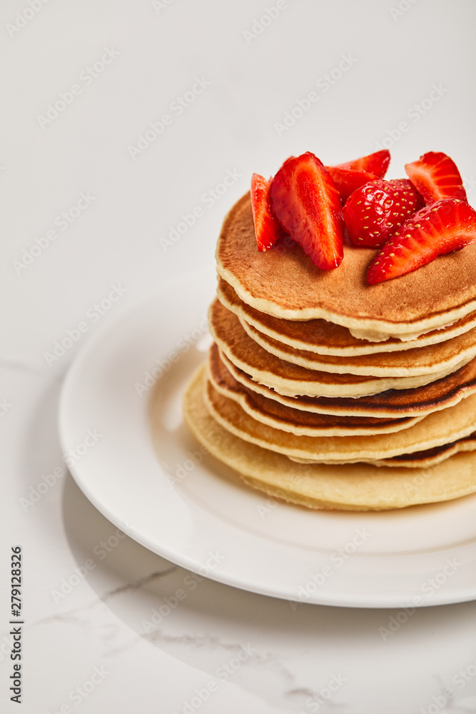 tasty pancakes with strawberries on white plate on textured surface