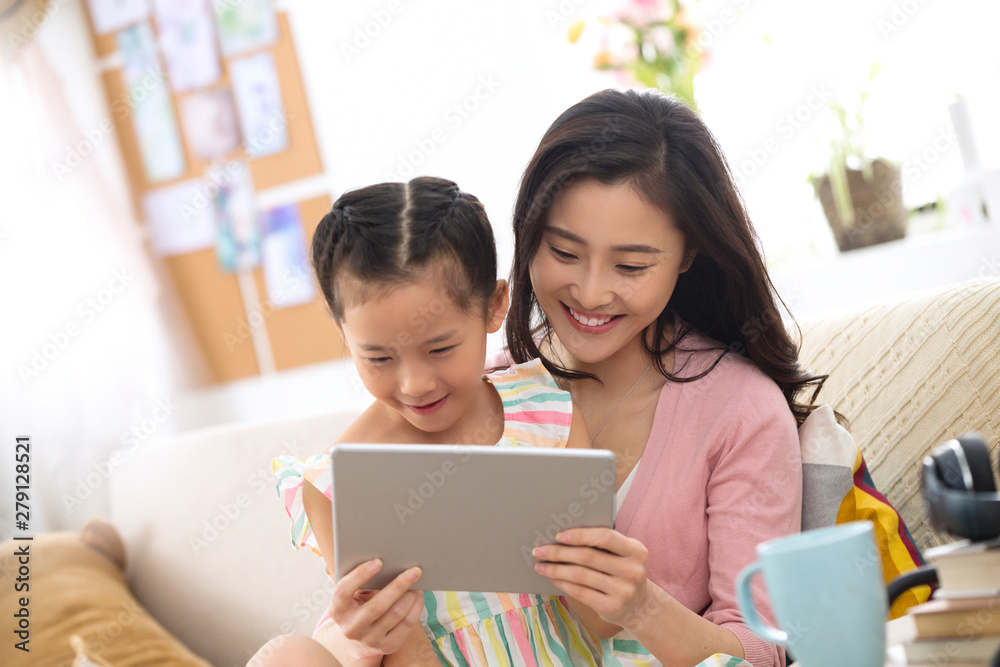 Happy mother and daughter at home watching the tablet Happy mother and daughter at home watching the tablet