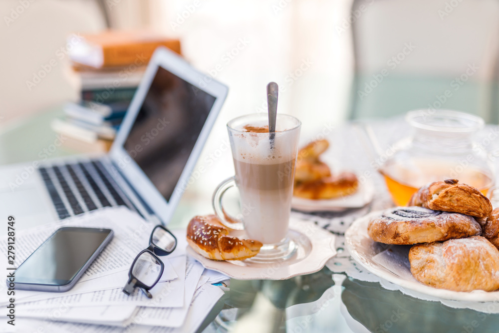 Home office, ideal working environment with breakfast. Luxury interior, glass table, reflection, notebook, eyeglasses, mobile phone and blurred background. Wellbeing at work. Home office, ideal working environment with breakfast. Luxury interior, glass table, reflection, notebook, eyeglasses, mobile phone and blurred background. Wellbeing at work.