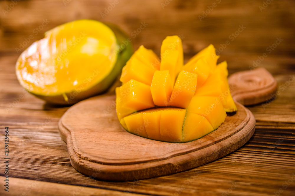 Cutting board with chopped mango fruit on a wooden table Cutting board with chopped mango fruit on a wooden table