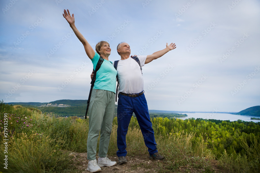 elderly couple on the top of mountain with hands up. Senior couple walking in nature. travel tourism concept elderly couple on the top of mountain with hands up. Senior couple walking in nature. travel tourism concept
