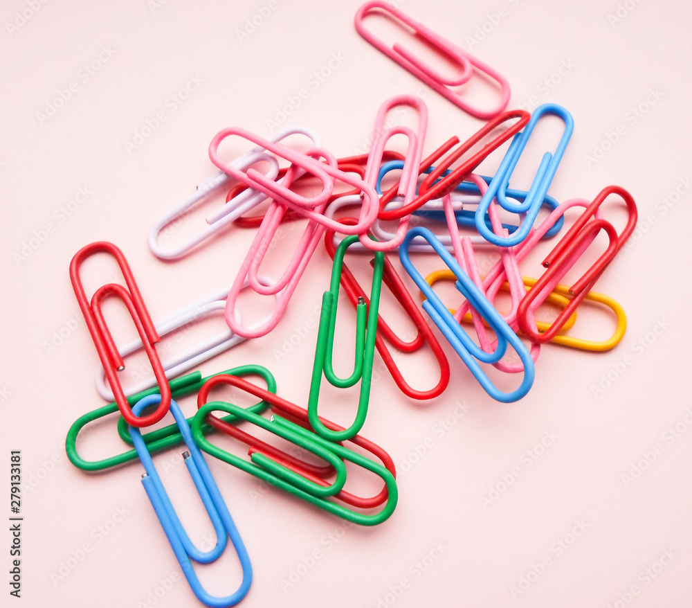 multicolored paper clips on a pink background. The concept is time to school. multicolored paper clips on a pink background. The concept is time to school.