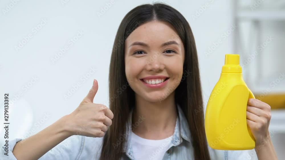 Smiling housewife holding washing gel and showing thumbs-up, customer review Smiling housewife holding washing gel and showing thumbs-up, customer review