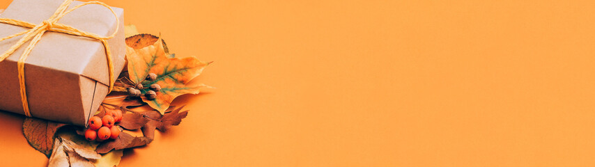 Creative birthday present. Beige handmade paper gift box with foliage decor on orange background. Copy space.