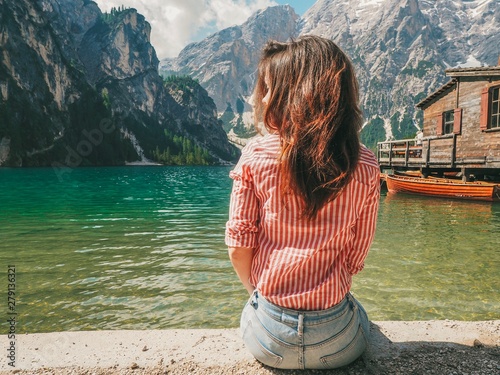 Girl with long hair in striped shirt in the background of Lake Lago di Braies in the Dolomites, South Tyrol, Italy. Pier with romantic old wooden rowing boats on the lake. Amazing view of lake Lago di © KseniaJoyg