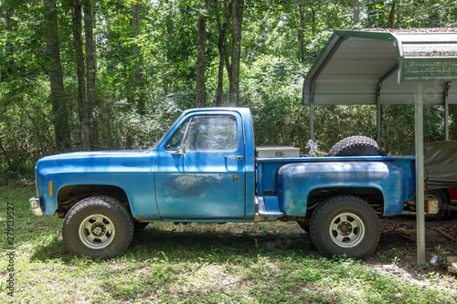 old vintage blue pickup truck parked in a backyard